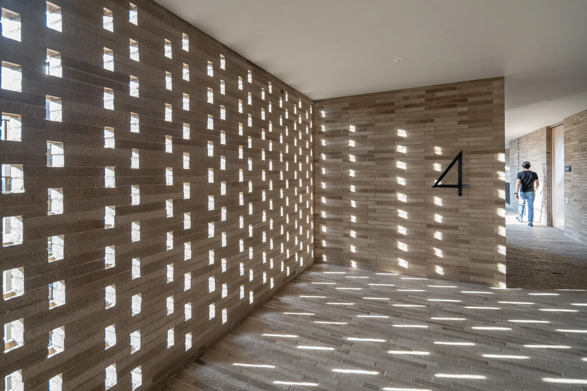 Juego de luces naturales y sombras de las vigas proyectadas en la fachada de concreto.
